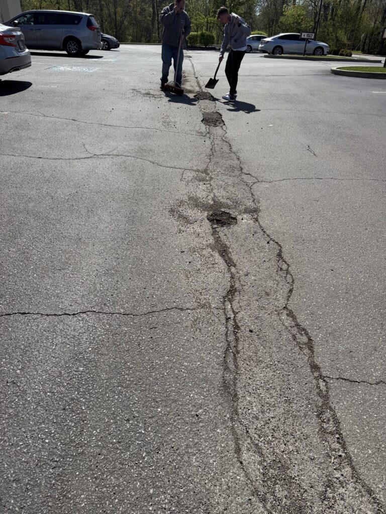 Picture of a Road patching Job. You can see a long crack with potholes.
