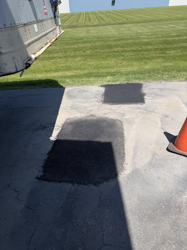 Picture of a new asphalt patch that was put in to cover up a hole in the road.